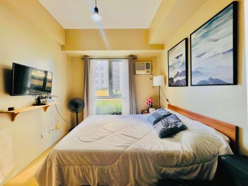 a bedroom with a bed and a television and a window at Avida Towers Atria in Iloilo City
