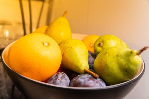 a bowl of fruit with pears oranges and other fruits at Jura Sport & Spa Resort in Saignelégier