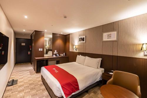 a hotel room with a bed and a desk at Ramada by Wyndham Jeju City Hall in Jeju