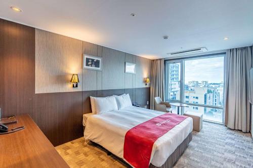 a hotel room with a bed and a large window at Ramada by Wyndham Jeju City Hall in Jeju