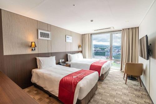 a hotel room with two beds and a window at Ramada by Wyndham Jeju City Hall in Jeju