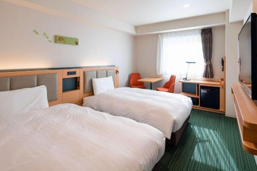 a hotel room with two beds and a television at Comfort Hotel Matsuyama in Matsuyama