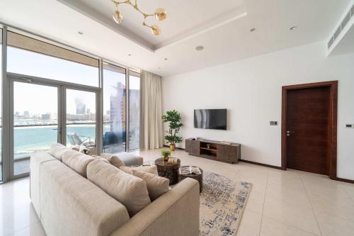 a living room with a large couch and a tv at Frank Porter - Diamond, Tiara Residences in Dubai