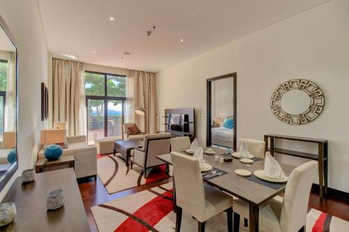 a dining room and living room with a table and chairs at Luxe Getaways Royal Amwaj Palm Jumeirah Resort Apartment Holiday Home in Dubai