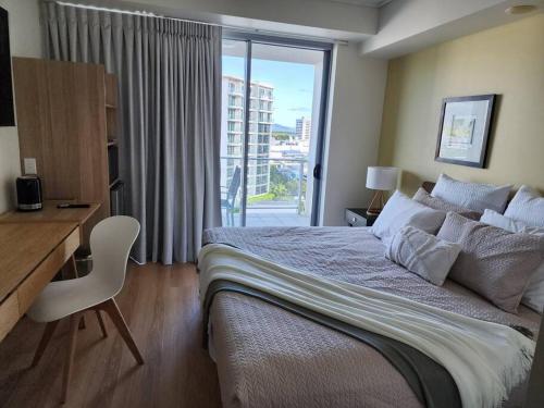 凯恩斯Studio room in Cairns Esplanade! Ocean view! Heart of Cairns的一间卧室，配有一张床、一张书桌和一扇窗户