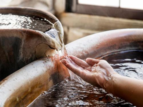 a person washing their hands in a copper sink at Arima Onsen Koki in Kobe