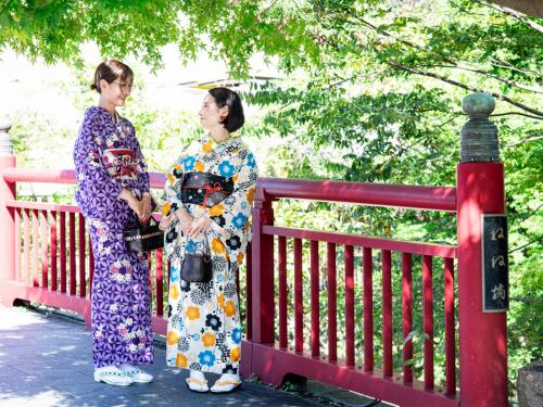 two women in kimonos standing next to a fence at Arima Onsen Koki in Kobe