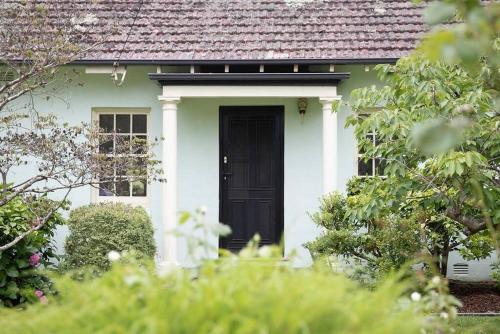 a green and white house with a black door at Merri Cottage in Bowral