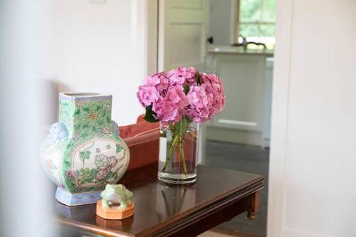 a table with two vases and a vase with pink flowers at Merri Cottage in Bowral