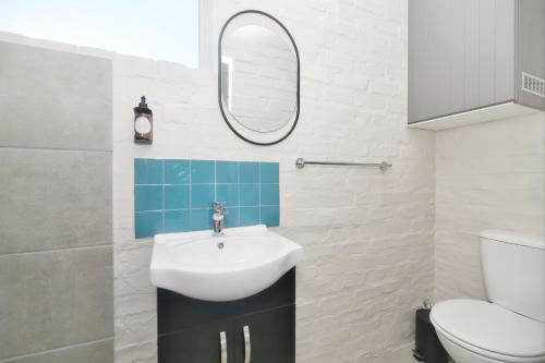 a bathroom with a sink and a mirror at Land's Edge Eco Friendly Cottages and Apartments in Struisbaai