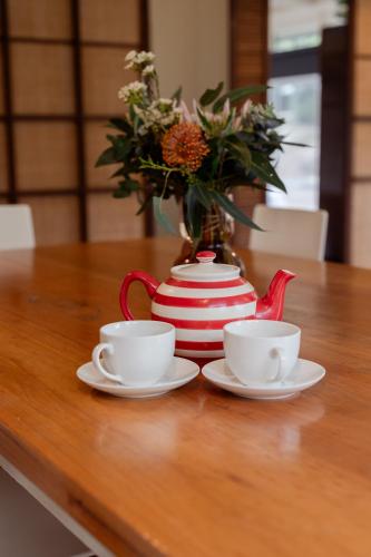 a table with two cups and a vase with flowers at My Seaclusion in Sorrento