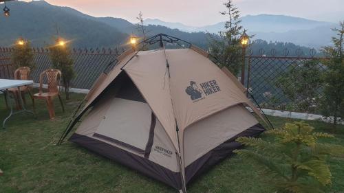 a tent sitting in the grass next to a table at Thumki Resort, Balthali in Panauti