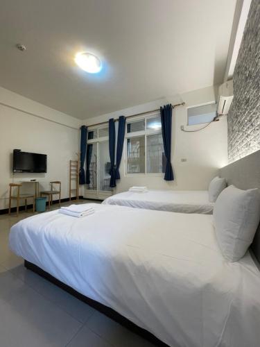 a bedroom with two beds and a flat screen tv at 依藍2館 in Jincheng