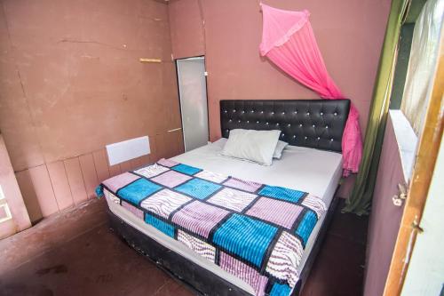 a bed in a small room with a pink wall at Pak Mus Guest House Ketambe - 0813-7072-1793 in Kutacane