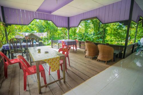 a patio with tables and chairs on a deck at Pak Mus Guest House Ketambe - 0813-7072-1793 in Kutacane