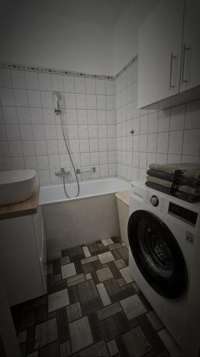 a bathroom with a tub and a washing machine at Lotti Apartman in Békéscsaba