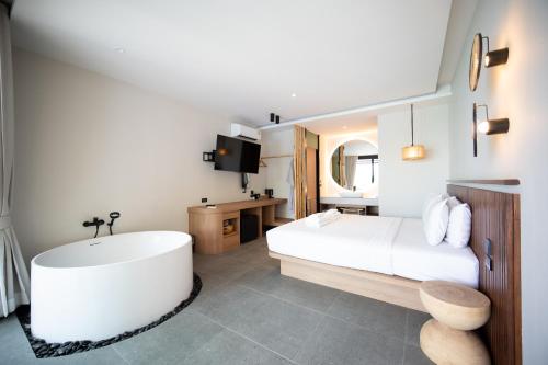 a bedroom with a large white bed and a bath tub at Sangthian Beach Resort in Ko Samed