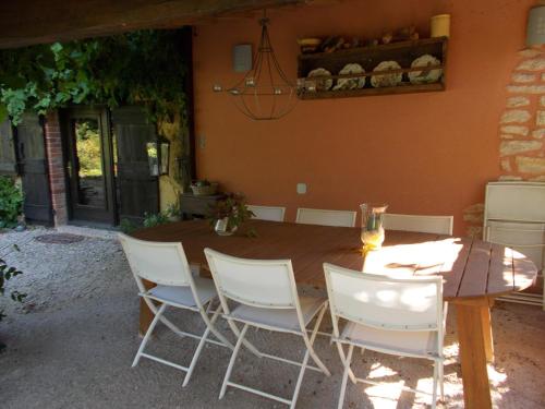 - une table en bois entourée de chaises blanches dans la cour dans l'établissement La Cassinette, à Romenay