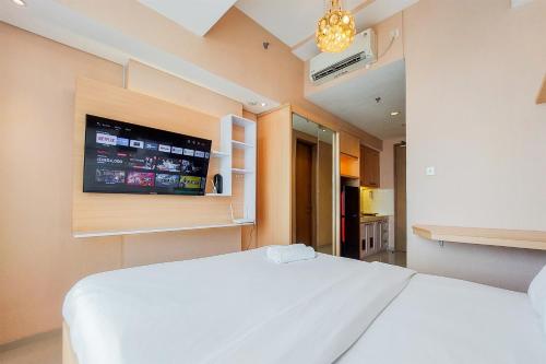 a bedroom with a white bed and a flat screen tv at Homey and Modern Studio at Tree Park City Cikokol Apartment By Travelio in Tangerang
