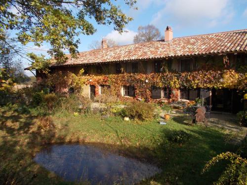 uma casa coberta de hera com um lago em frente em La Cassinette em Romenay