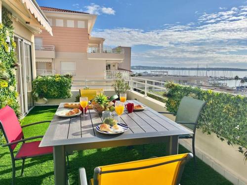une table avec des assiettes de nourriture sur un balcon dans l'établissement Azur Riviera YourHostHelper, à Vallauris