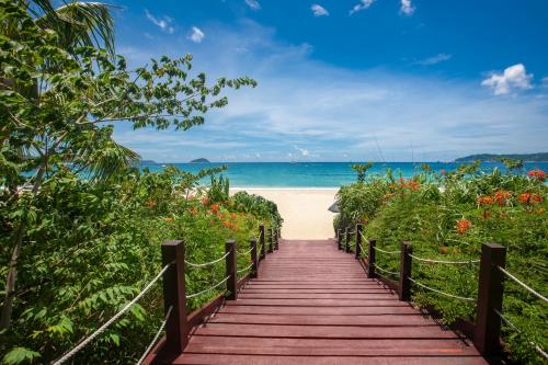 un chemin en bois menant à une plage fleurie dans l'établissement Yalong Bay Mangrove Tree Resort, à Sanya