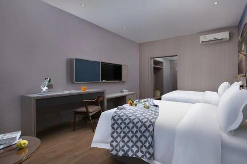 a hotel room with a bed and a desk and a tv at Xiyatu Hotel-Henglan Branch in Zhongshan