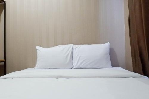 a bed with white sheets and pillows at Comfy and Exclusive 2BR Apartment at Tanglin Supermall Mansion By Travelio in Surabaya