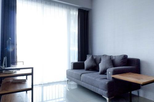 a living room with a couch and a table at Comfy and Exclusive 2BR Apartment at Tanglin Supermall Mansion By Travelio in Surabaya