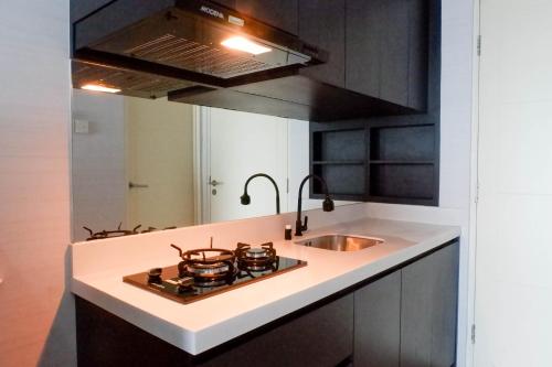 a kitchen with a stove and a sink at Comfy and Exclusive 2BR Apartment at Tanglin Supermall Mansion By Travelio in Surabaya