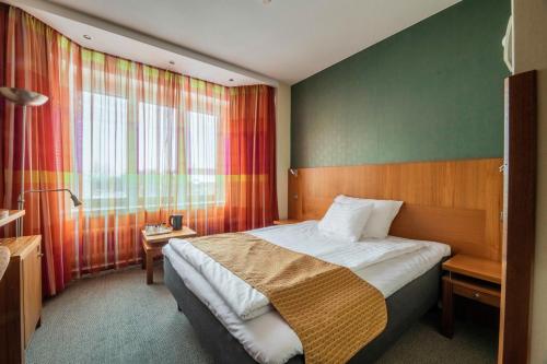a hotel room with a bed and a window at Hotel Oscar in Varkaus