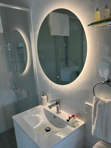 ein weißes Badezimmer mit Waschbecken und Spiegel in der Unterkunft Robyn's Nest - Bed and Breakfast in Tewantin