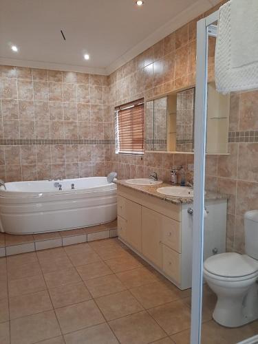 a bathroom with a tub and a toilet and a sink at Matalatala Wildlife Lodge in Roodeplaat