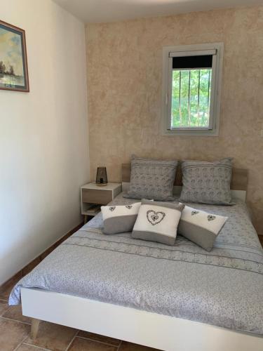 une chambre avec un lit avec des oreillers et une fenêtre dans l'établissement Aux IRIS, à Flayosc