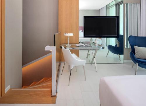 a bedroom with a bed and a desk and a tv at SLS Dubai Hotel & Residences in Dubai