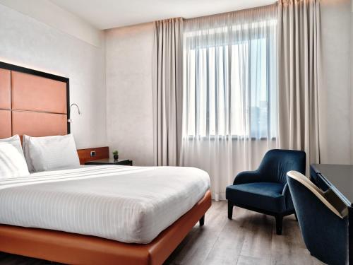 a hotel room with a bed and a blue chair at Crowne Plaza Milan - Malpensa Airport by IHG in Case Nuove