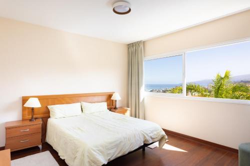 ein Schlafzimmer mit einem Bett und einem großen Fenster in der Unterkunft El Estanque - Vivienda vacacional in Puerto de la Cruz