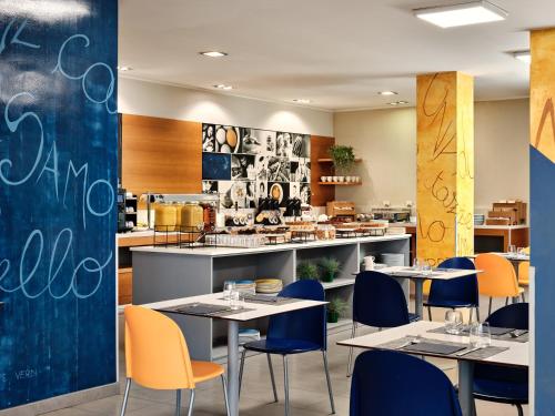 a restaurant with tables and chairs and a kitchen at Holiday Inn Express Milan-Malpensa Airport by IHG in Case Nuove