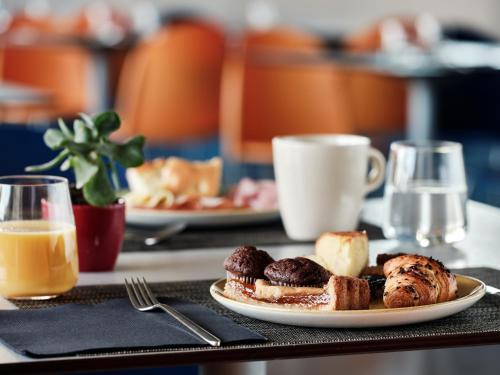 a table with a plate of pastries and a cup of coffee at Holiday Inn Express Milan-Malpensa Airport by IHG in Case Nuove