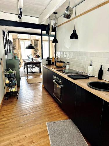 une cuisine avec des armoires noires et un plancher en bois dans l'établissement La Maison des Vignes - Terrasse & balcon, à Morlaix