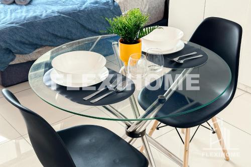 a glass table with chairs and plates and a plant at FREE Streaming Services-Designed Studio Home at Cybersquare, Cyberjaya by Flexihome-MY in Cyberjaya