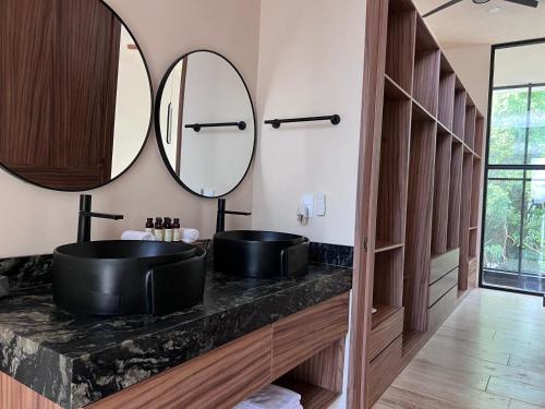 a bathroom with two sinks and two mirrors at Villa Escondida - Riviera Maya in Puerto Morelos