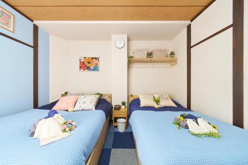 a bedroom with two beds and a clock on the wall at Belmont 303 3min to Station Easy Access Ueno Asakusa Skytree Sleeps 4 in Tokyo