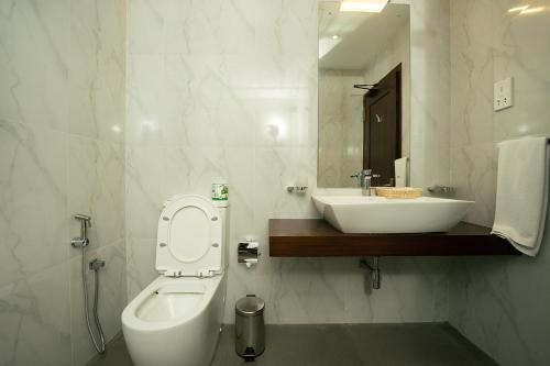 a bathroom with a sink and a toilet and a mirror at Good wood Airport Hotel in Katunayaka