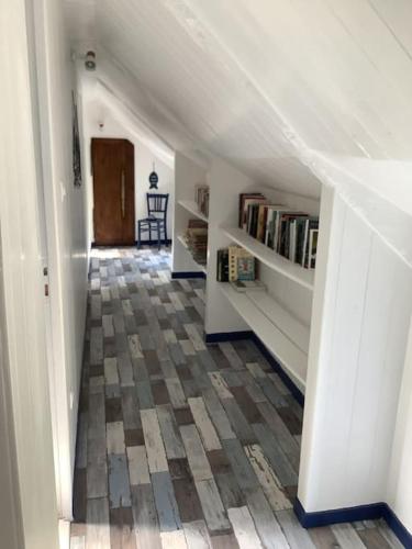 un couloir mansardé avec escalier et étagère. dans l'établissement Longère terre mer, à Plélo