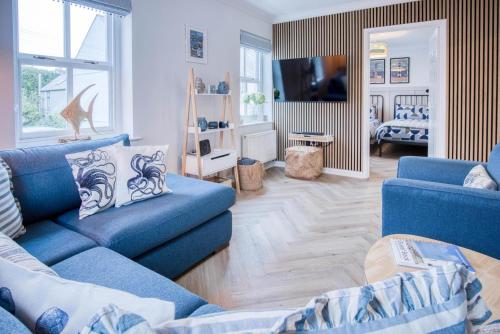 a living room with two blue couches and a television at Kilmore House - 2 Bedroom Apartment - Tenby in Tenby