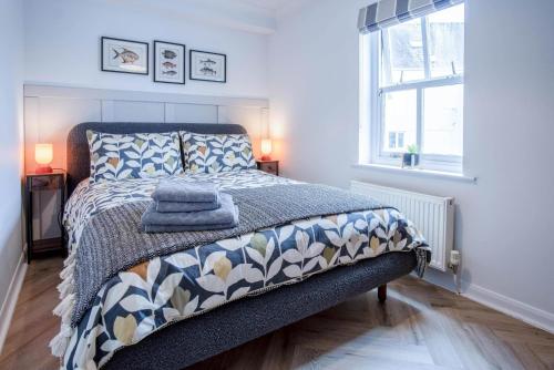 a bedroom with a bed with a blanket and a window at Kilmore House - 2 Bedroom Apartment - Tenby in Tenby