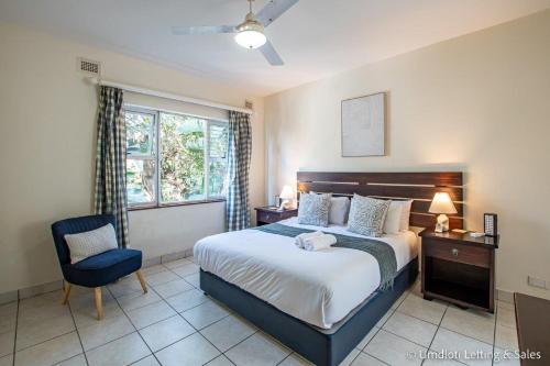 a bedroom with a bed and a chair and a window at Coastal Nest in Durban North