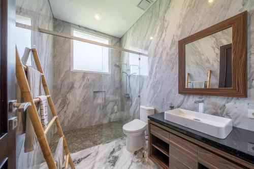 a bathroom with a sink and a toilet and a mirror at Adara Lake View Residence Bedugul - Bali in Bedugul
