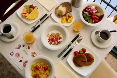 a table with plates of breakfast foods and cups of coffee at Termini Beach Hotel & Suites in Lido di Jesolo